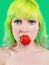 Beautiful girl with color hair holds strawberry with lips on green background