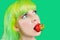 Beautiful girl with color hair holds strawberry with lips on green background