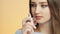 Beautiful girl on a colored studio background enjoying the aroma of perfume from a bottle, a young woman sniffs and poses, the con