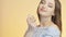 Beautiful girl on a colored studio background enjoying the aroma of perfume from a bottle, a young woman sniffs and poses, the con