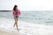 Beautiful girl with colorful windbreaker running on the beach