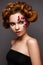 Beautiful girl with creative make-up with floral appliques. The model in the style of romantic with flower petals around her