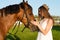 Beautiful girl with a crown caress horse outdoors