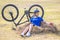 Beautiful girl cyclist sitting on dry grass on the background of the bike. Nature and man