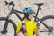 Beautiful girl cyclist in yellow with tea and thermos in hand on the background of sand. Sports and recreation