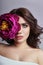 Beautiful girl with dark hair and big flower near face. Large pu