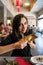 Beautiful girl with dark hair, dressed in black is holding a plate full of meat rolls and chilly sauce