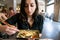 Beautiful girl with dark hair, dressed in black is holding a plate full of meat rolls and chilly sauce