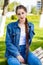 Beautiful girl in a denim jacket sits on a bench in a summer park