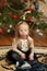 Beautiful girl with Down syndrome sits near a Christmas tree