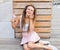 Beautiful girl with dreadlocks in pink skirt sitting on the veranda and eating colorful ice-cream cone on a warm summer evening.