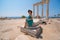 A beautiful girl in a dress, hat and sunglasses poses with a view of the ruins of the ancient Roman temple of Apolon. Side, Turkey