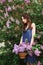 Beautiful girl in a dress posing near a Bush of lilacs on a summer day, purple flowers in the Park. Spring portrait of a girl