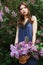 Beautiful girl in a dress posing near a Bush of lilacs on a summer day, purple flowers in the Park. Spring portrait of a girl