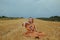 A beautiful girl in a dress sits on a wheat field. Fabulous photo of a blonde outside the city. A woman without allergies holds