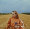 A beautiful girl in a dress sits on a wheat field. Fabulous photo of a blonde outside the city. A woman without allergies holds