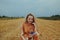 A beautiful girl in a dress sits on a wheat field. Fairytale portrait of a blonde outside the city. Girl without allergies holding