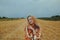 A beautiful girl in a dress sits on a wheat field. Fairytale portrait of a blonde outside the city. Girl without allergies holding