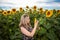 Beautiful girl in a dress standing in a sunflower field and holding a sunflower