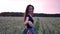 Beautiful girl in dress walking in through field touching wheat ears at sunset.