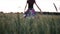 Beautiful girl in dress walking in through field touching wheat ears at sunset.