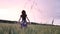 Beautiful girl in dress walking in through field touching wheat ears at sunset.