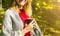 Beautiful girl drinking coffee in autumn wood. A cup with hot drink. Cosy mood. Red and yellow leaves. Beautiful nature. Stylish