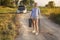 The beautiful girl driver in the car ran out of fuel, and she walks along a rural road with an empty fuel tank