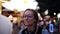 Beautiful girl eating cotton candy in an amusement park near the blurred carousel. Wearing trendy glasses, happy