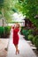 Beautiful girl in elegant dress and hat and charming smile posing for the photographer in the park.