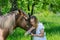 Beautiful girl embraces muzzle of chestnut horse and laughs