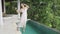 A beautiful girl in evening pink with a glass of wine started talking on the phone and tripped and fell into the pool. A