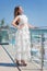 A beautiful girl in a fantastic dress on a resort background. The charming girl in a white dress. Beauty and fashion concept.