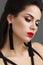 Beautiful girl with the fashion make-up, red lips, long black earrings and black arrows