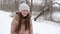 Beautiful girl with fluttering hair is smiling while walking in park in a blizzard in winter. Slow motion.