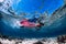 Beautiful girl freediver swim over sandy sea bottom with United States flag