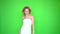 Beautiful girl full of energy in white dress dancing and singing isolated on green screen background