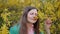 Beautiful girl in green jacket smelling flower among yellow blossom tree