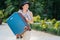 Beautiful girl in a hat holds a larger blue suitcase.