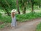 Beautiful girl in a hat and long hair is standing on a footpath in a green forest