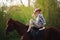 Beautiful girl in a hat riding a horse in countryside