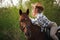 Beautiful girl in a hat riding a horse in countryside