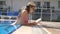 Beautiful girl in hat and sunglasses reading book at pool. Young woman relaxing at warm sunny day during vacation