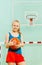 Beautiful girl holding ball under basketball hoop