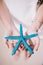 A beautiful girl holding blue five point starfish in his hands on the white sandy beach