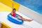 Beautiful girl on inflatable ring riding water slide with hand up in aqua park