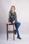 Beautiful girl in jeans sits modern people model on a high chair studio lifestyle