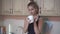 Beautiful girl in the kitchen. A blonde in a black top drinks tea or coffee from a white mug in the kitchen.