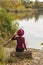 Beautiful girl on the lake. Beautiful girl in a hat. Girl in a burgundy hat and a burgundy sweater. Autumn photo.