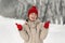 Beautiful girl laughs and shows class on snow background. Young woman in comfortable winter clothes walks in park